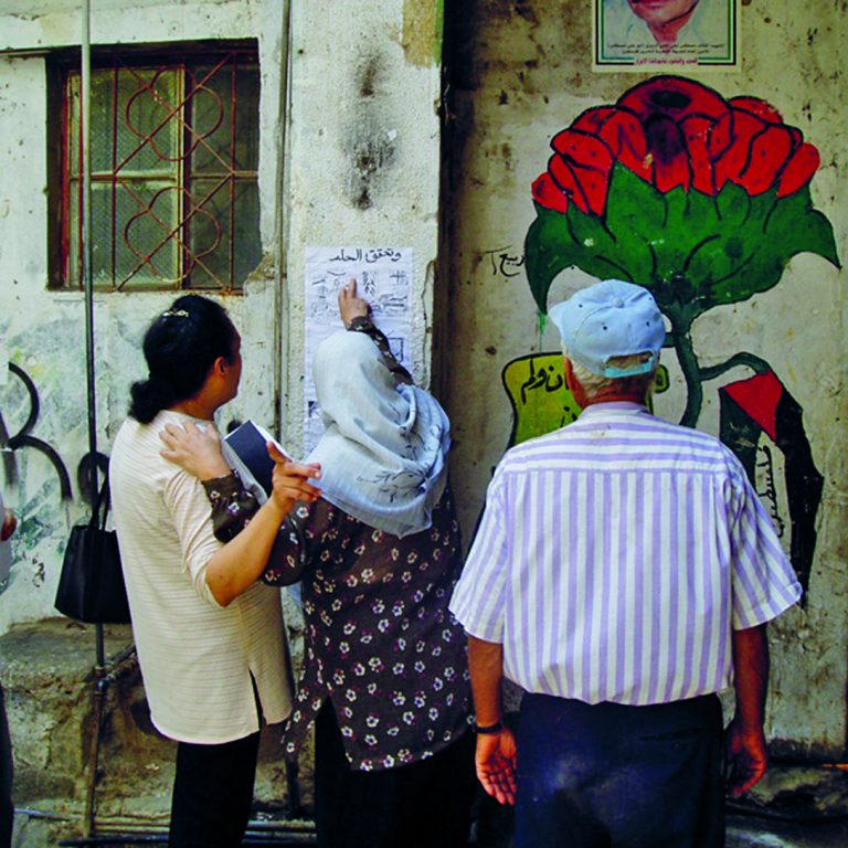 Libanonilaisia katsomassa seinälle ripustettua sarjakuvaa.