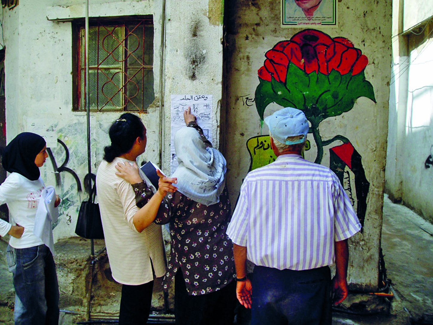 Libanonilaisia katsomassa seinälle ripustettua sarjakuvaa.