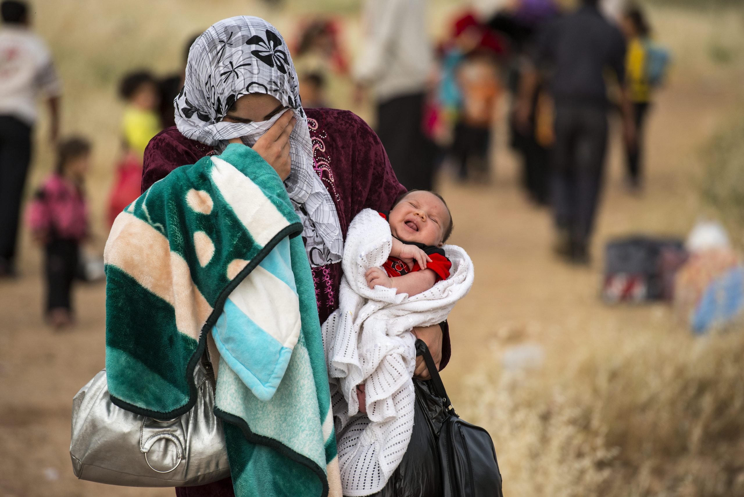 Syyrialaisäiti kantaa kuukauden vanhaa lastaan yli Irakin rajan vuonna 2013.