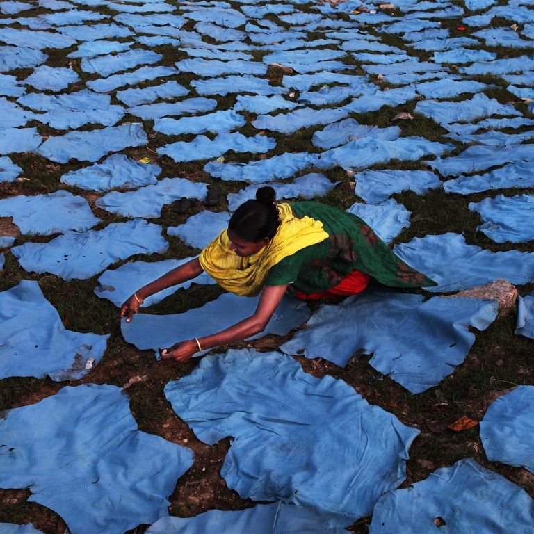 Naisyrittäjä Bangladeshissa levittää nahkaa kuivumaan.