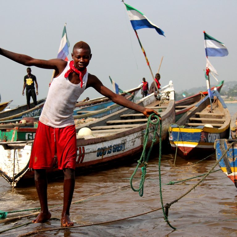 Sierraleonelainen poika rannalla kalastusveneiden keskellä.