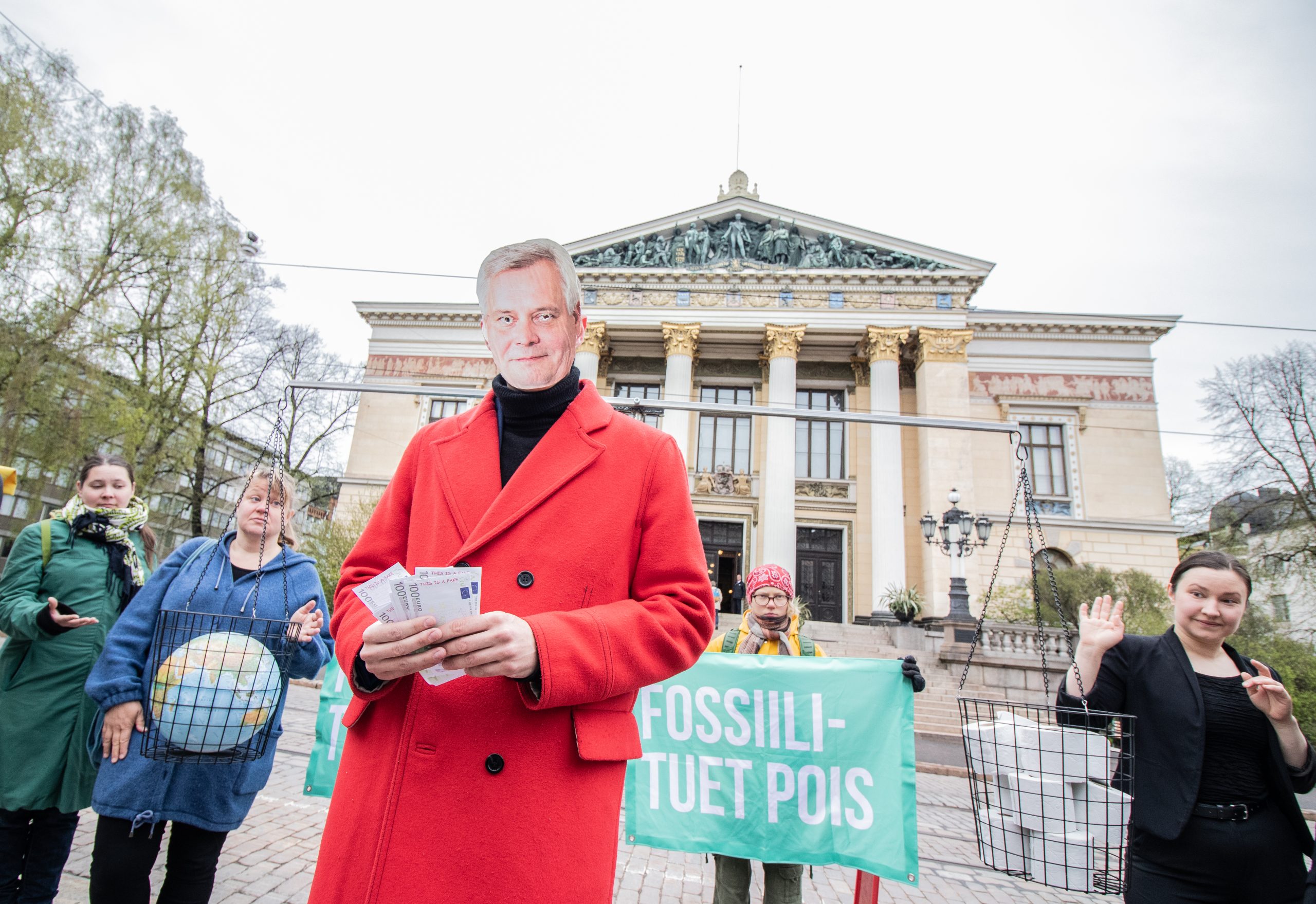 Antti Rinteeksi pukeutunut aktivisti pitelee seteleitä Säätytalon edellä järjestötempauksessa.