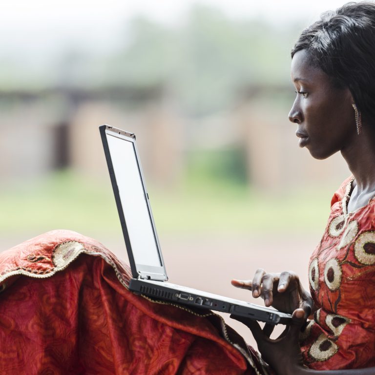 afrikkalaisnainen pitelee kannettavaa tietokonetta polvillaan