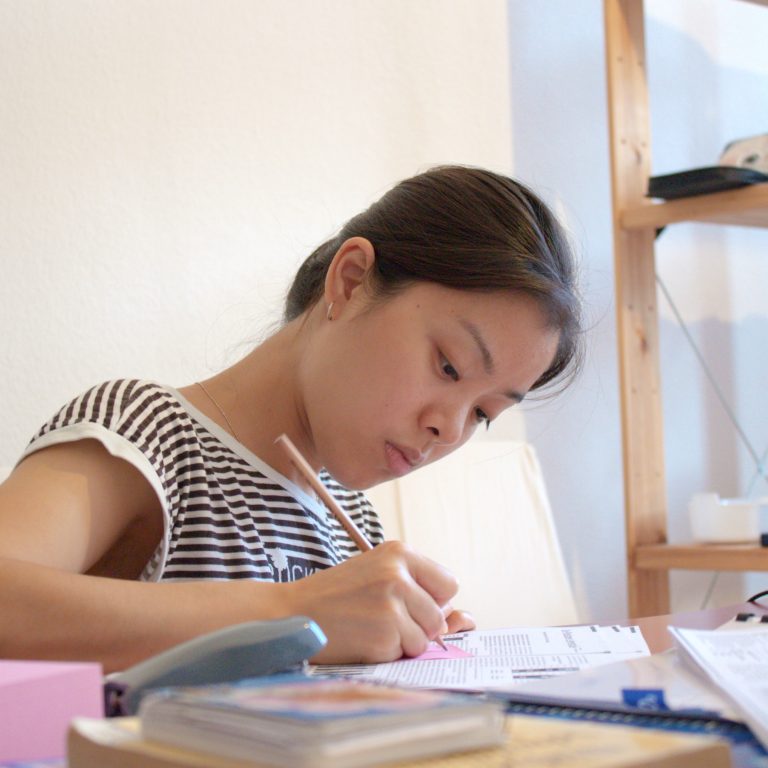 Aasialaistaustainen nainen opiskelee pöydän ääressä.