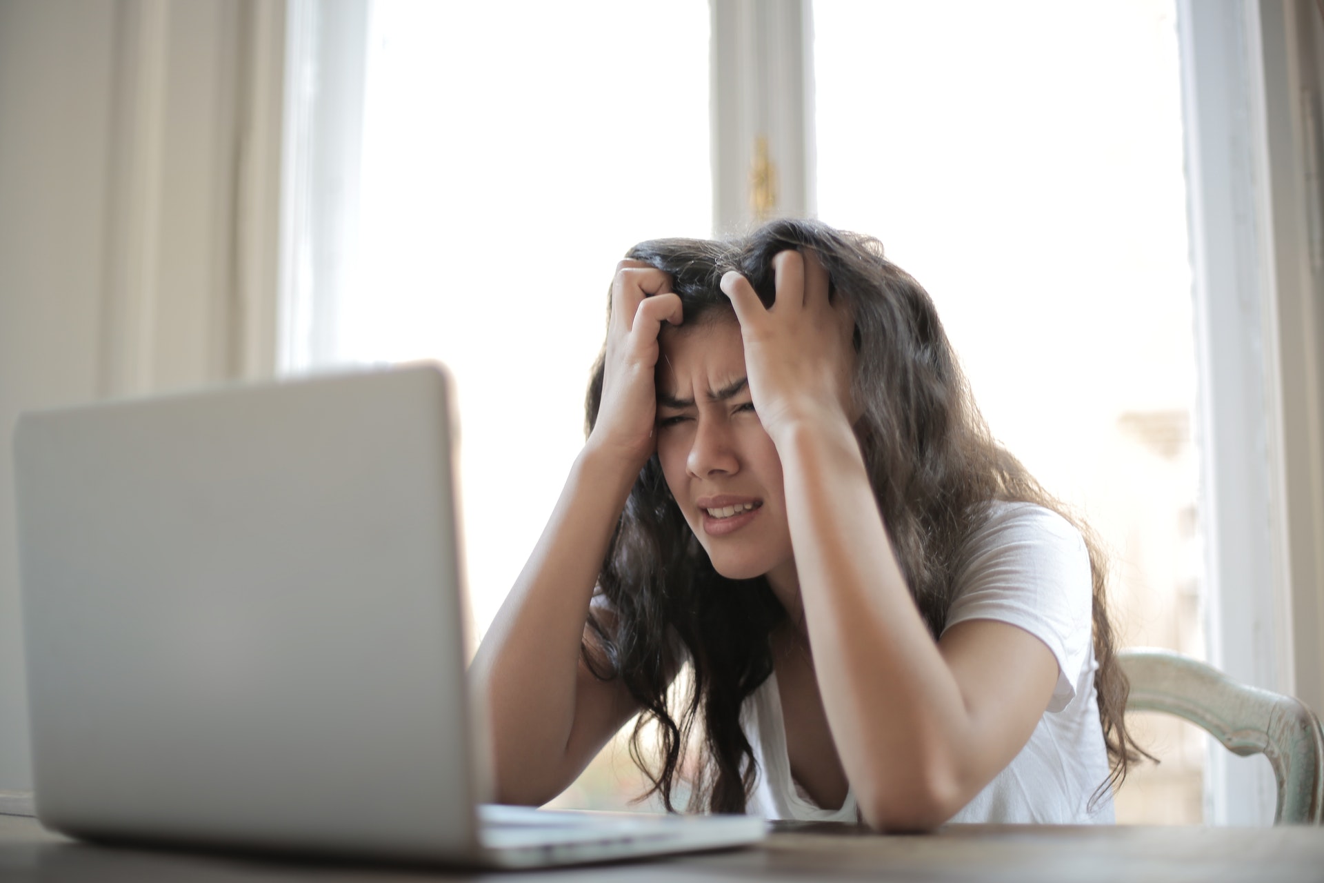 Nainen tuijottaa tietokoneen ruutua turhautuneena