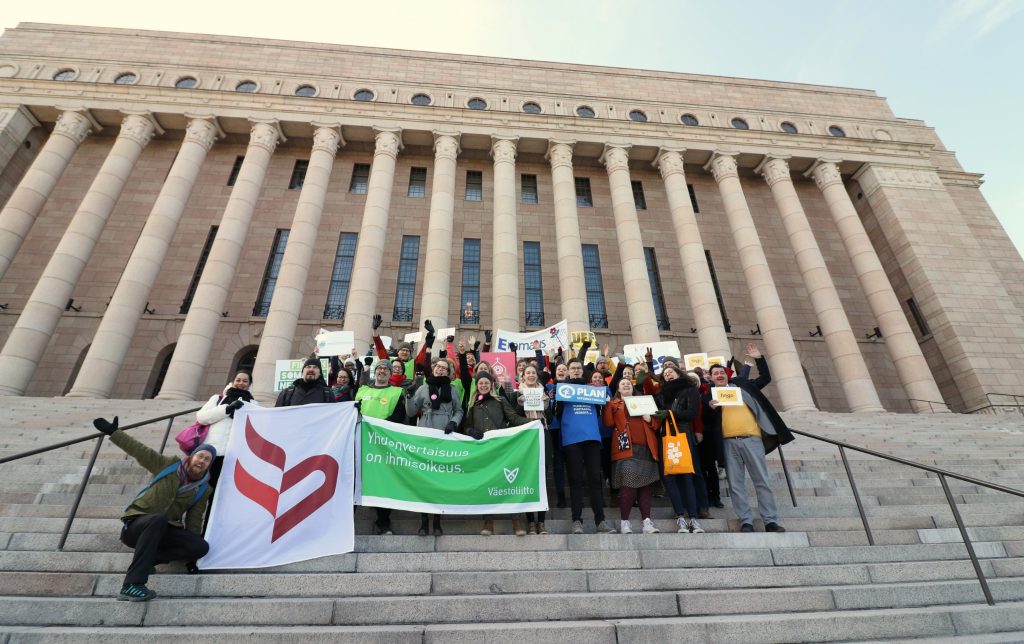 Joukko järjestöihmisiä Eduskuntatalon portailla.