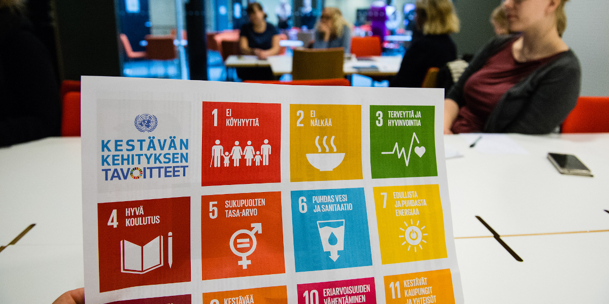 A person holds a paper with Sustainable Development Goal icons.
