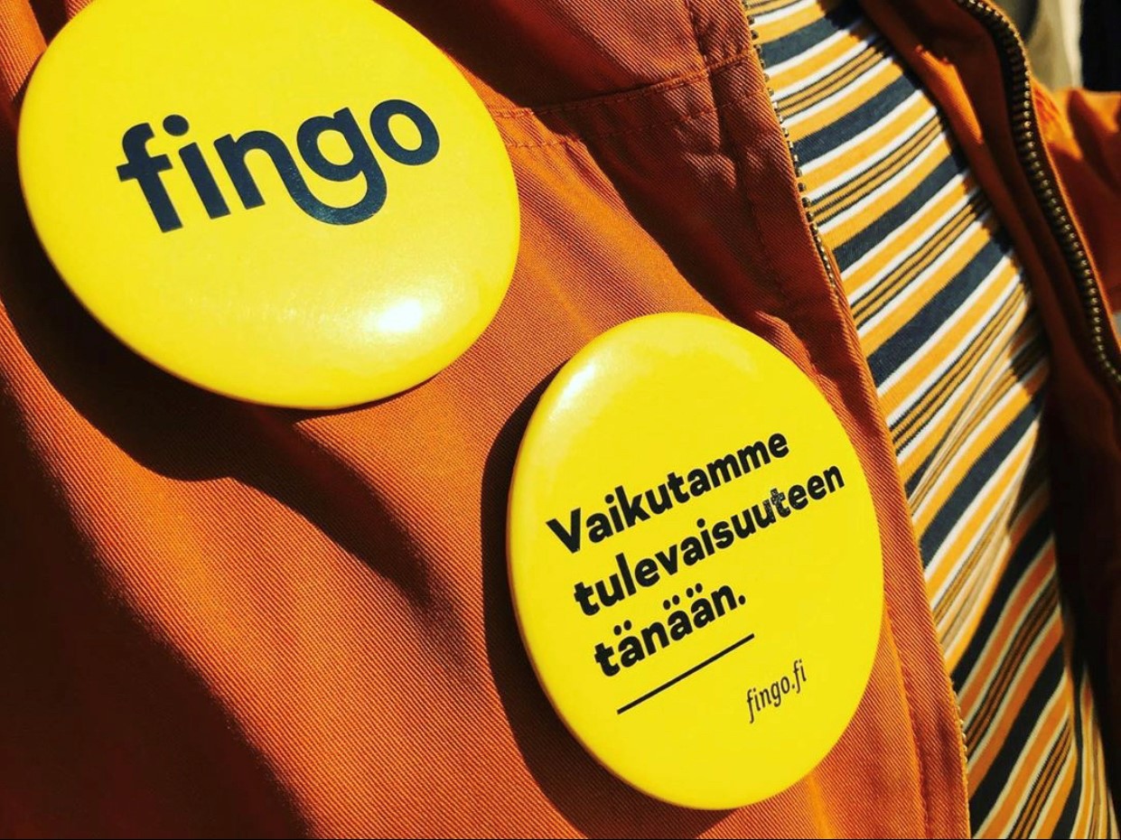 Kaksi keltaista rintanappia, joista toisessa Fingon musta logo ja toisessa teksti ' Vaikutamme tulevaisuuteen tänään'.