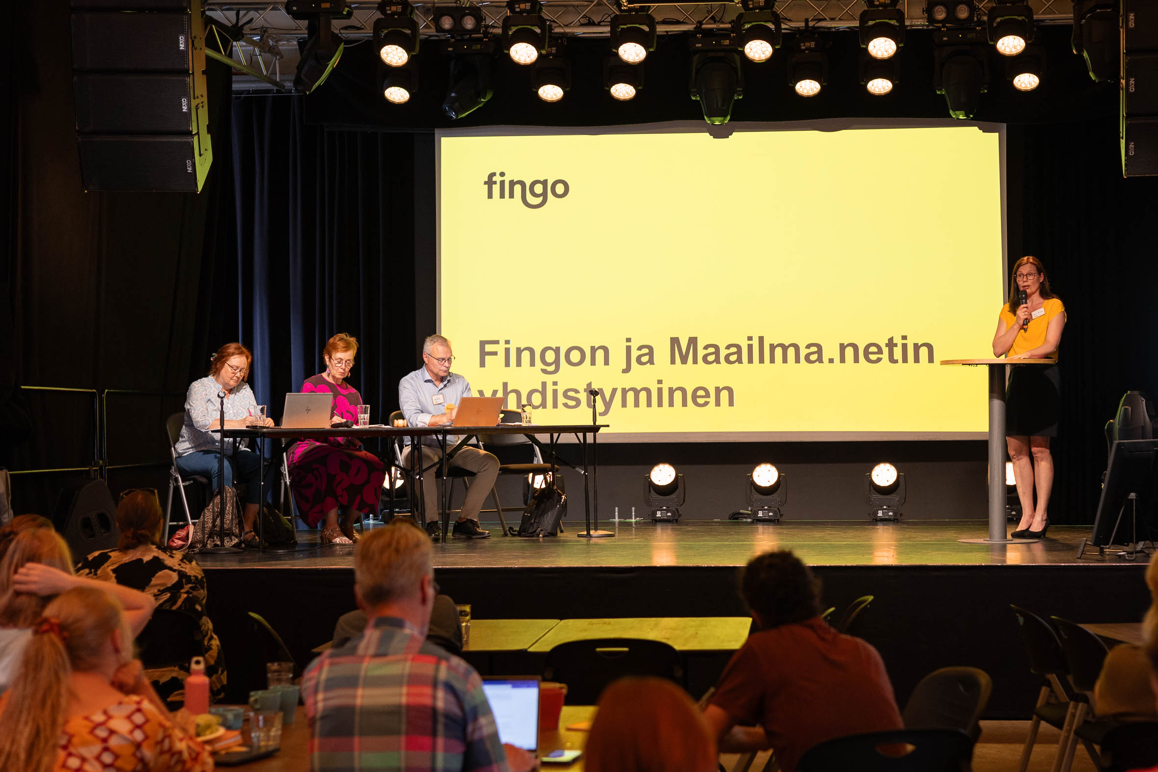 Kuvassa Fingon kevätkokouksessa käsitellään Fingon ja Maailma.netin yhdistymistä. Kuvassa kokouksen puheenjohtajistoa ja yleisöä.