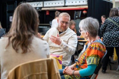 Kaksi henkilöä istuu pöydän ääressä ja keskustelee.