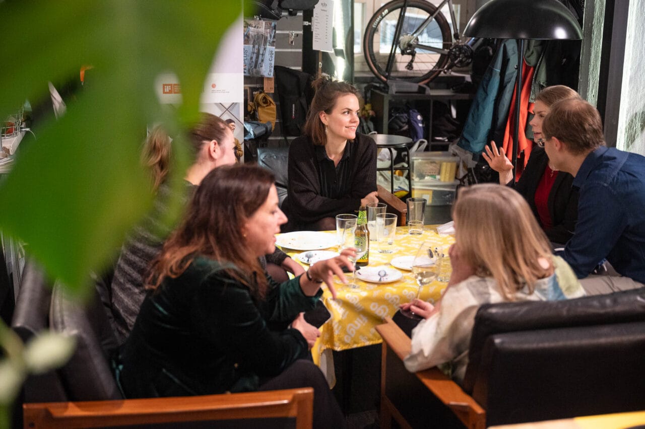 Ihmisiä istuu pöydän ympärillä.