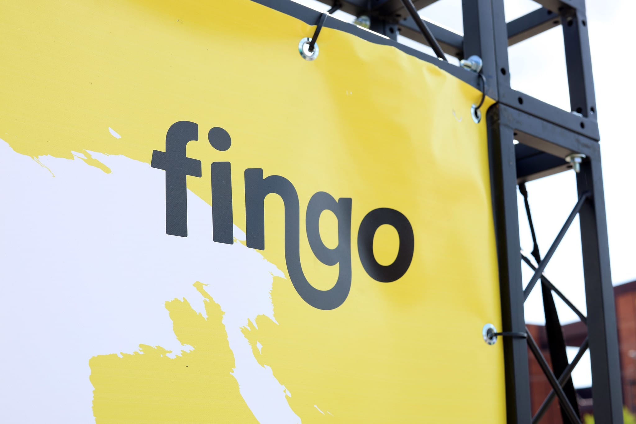 Fingon logo, jossa pala maailmankarttaa taustalla. Kangas kiinnitettynä trussitelineisiin.