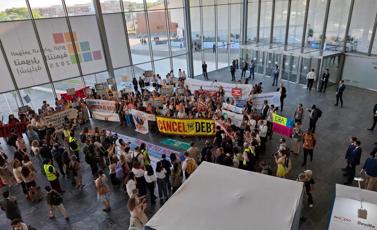 Kansalaisyhteiskunnan edustajat ilmaisevat mieltään Sevillassa järjestetyssä kestävän kehityksen rahoituksen konferenssissa kesällä 2025.