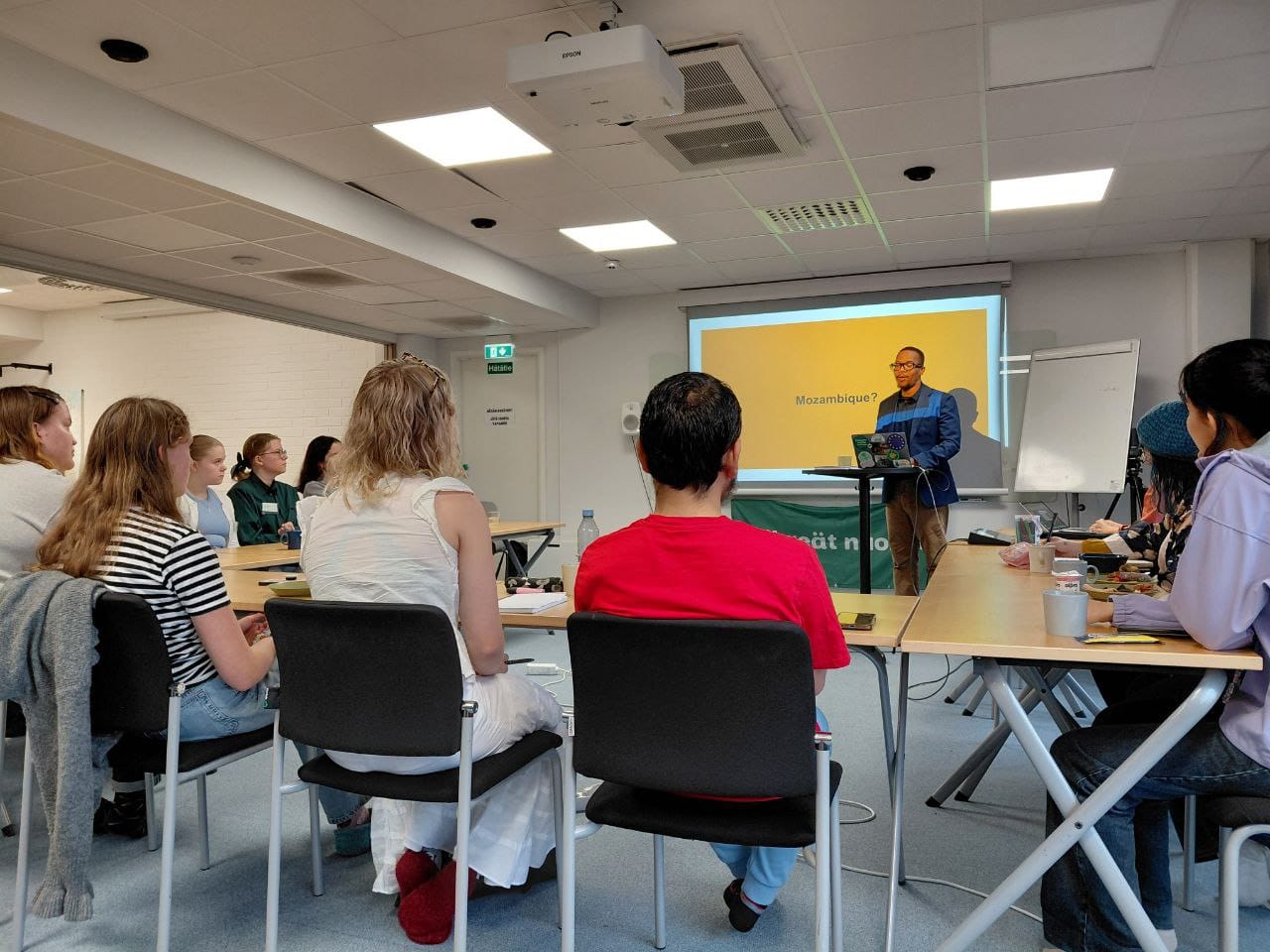 Ihmisiä istuu luokassa kuuntelemassa puhujaa.|Ryhmäkuva.|Henkilö näyttää power point -esitystä.|Kaksi henkilöä pitää työpajaa.|Kuvakortteja.