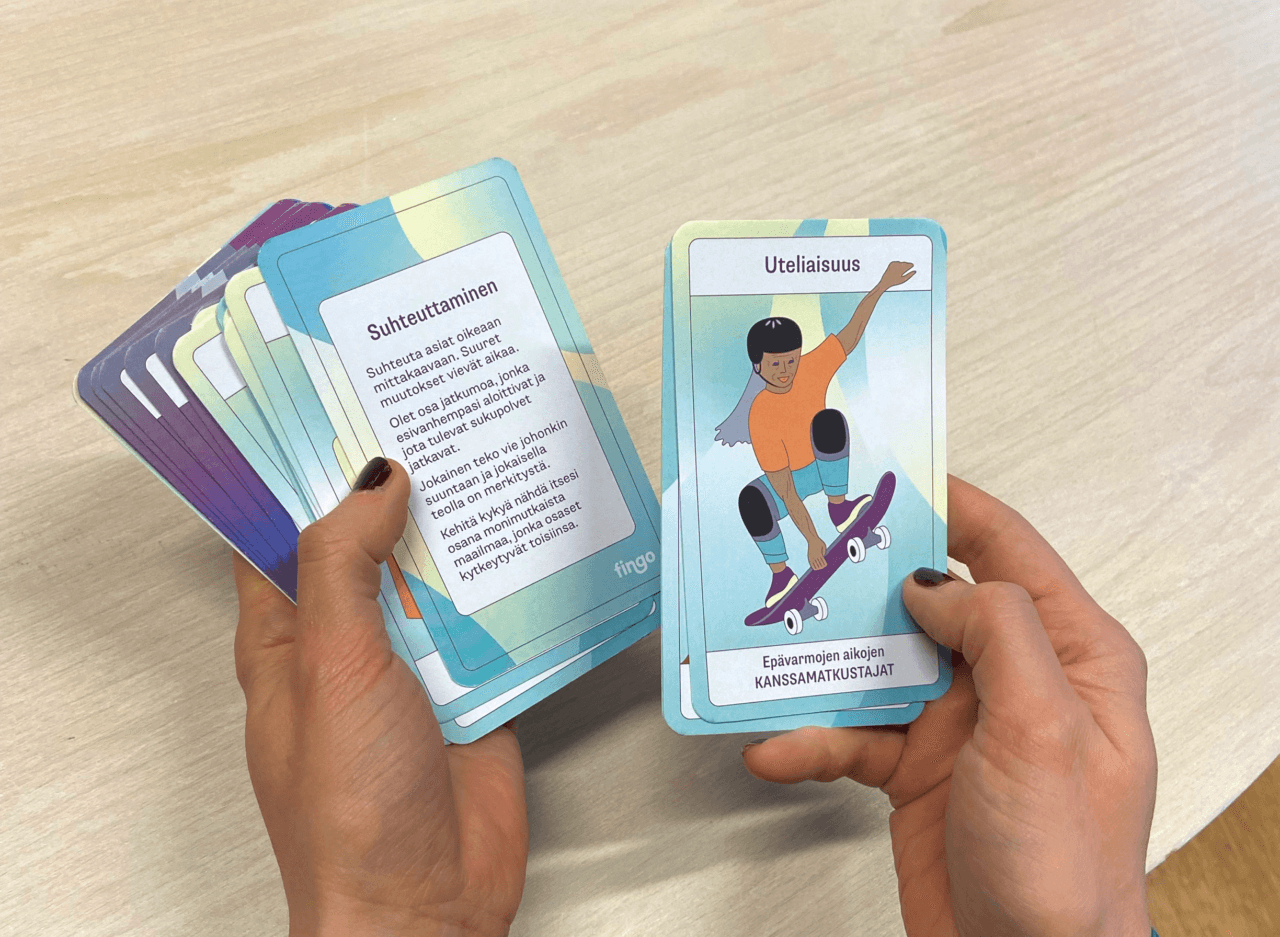 Henkilö selaa korttipakkaa käsissään.|Henkilö selaa korttipakkaa käsissään.|