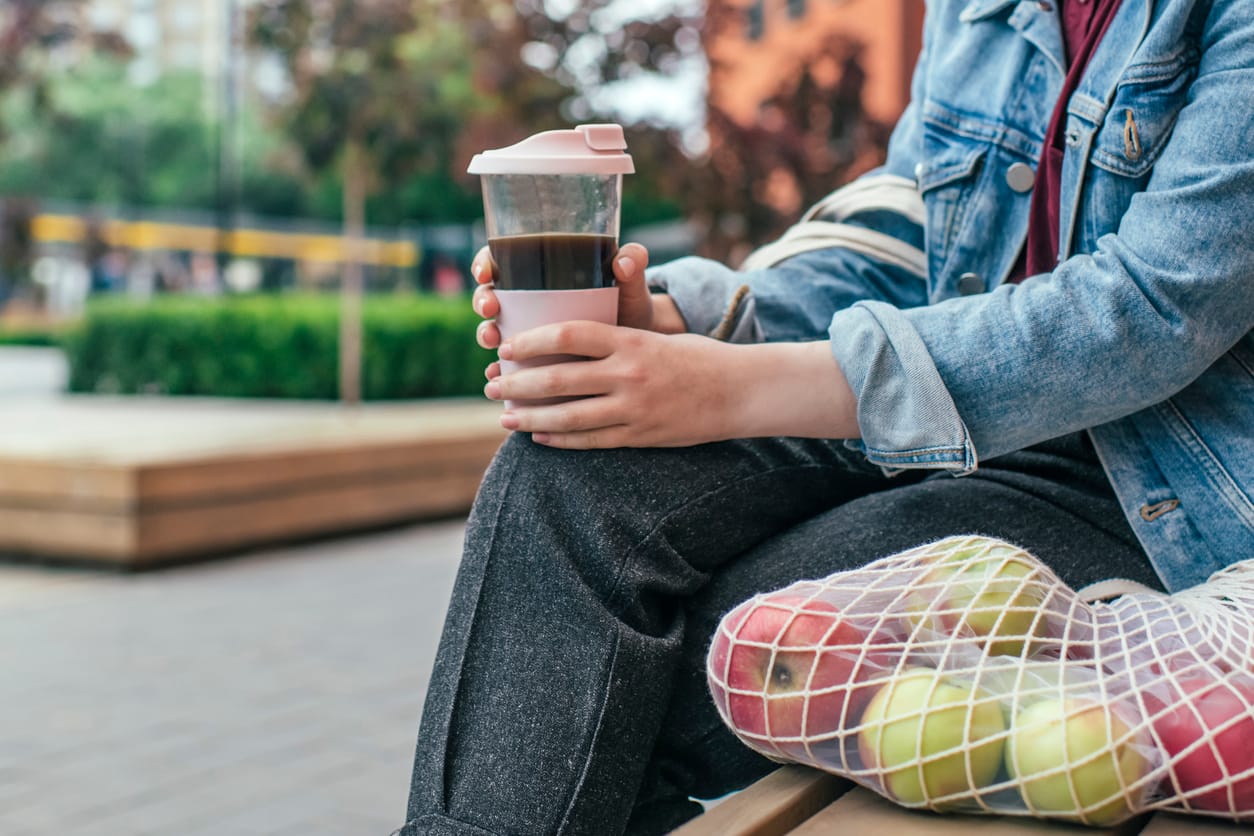 Henkilö pitelee kestokahvikuppia