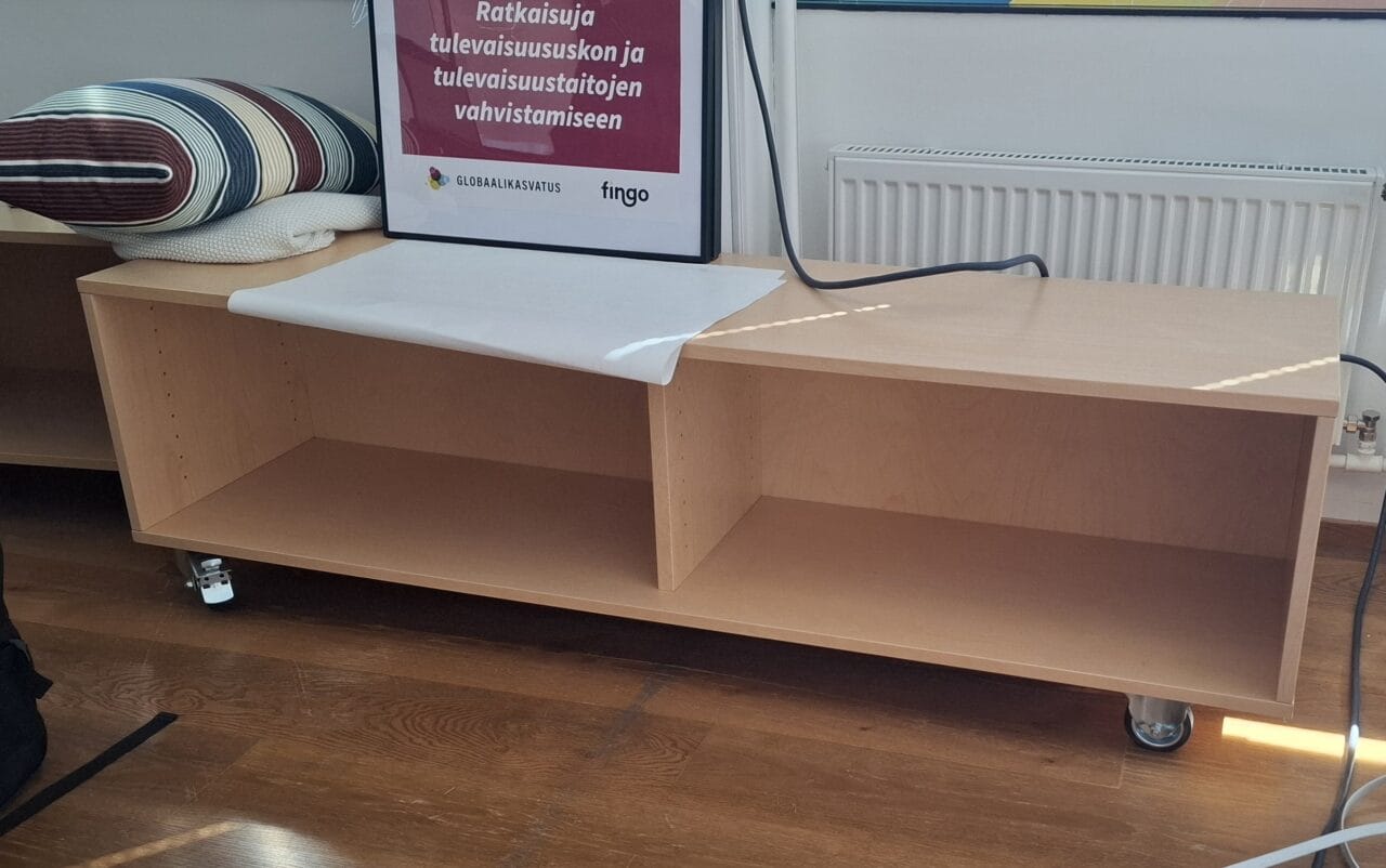 Kuvassa on matala taso, jossa on neljä pyörää liikuttelua varten.